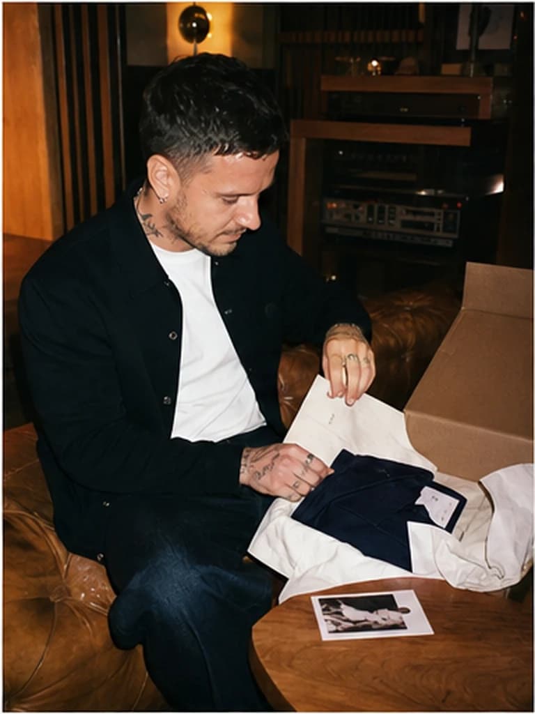 Founder checking a garment and paperwork beside an open box